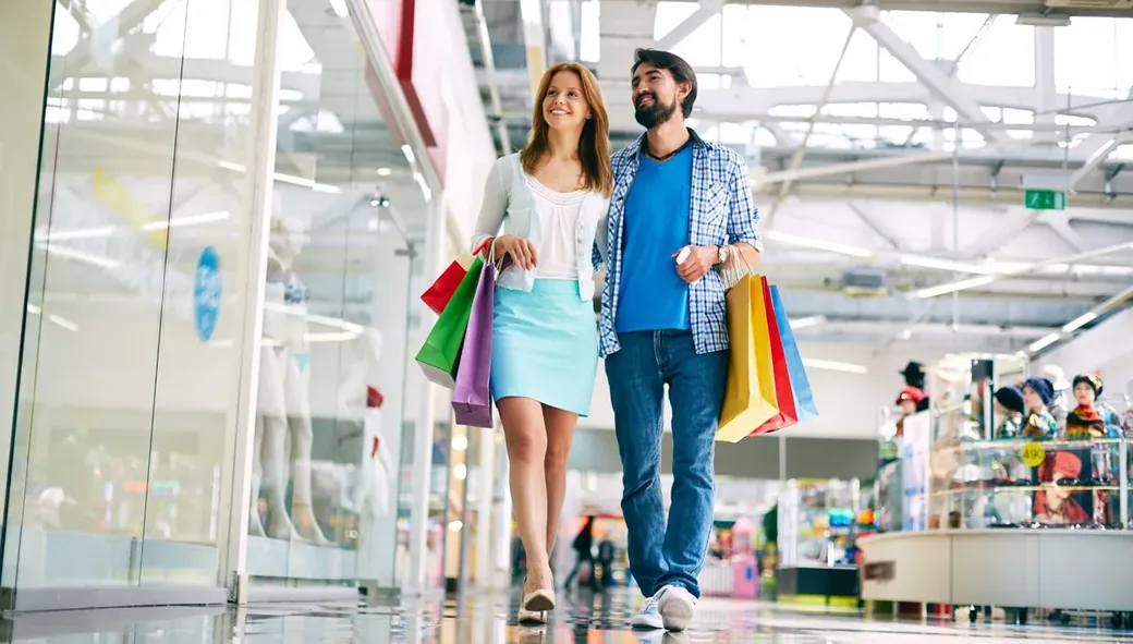 Casal caminhando com sacolas de compras em shopping